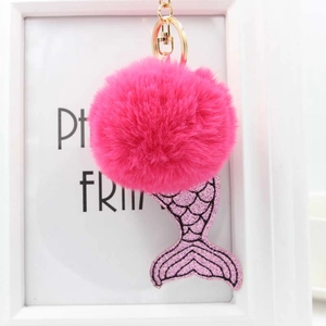 Détail du pendentif sirène à paillettes et pompon en fourrure magenta sur porte-clés doré
