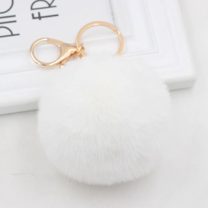 Detail shot of white faux rabbit fur pom pom with gold metal lobster clasp and keyring