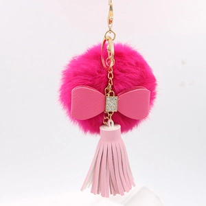 Close-up of bright pink faux fur pompom keychain with rhinestone bow and leather tassel