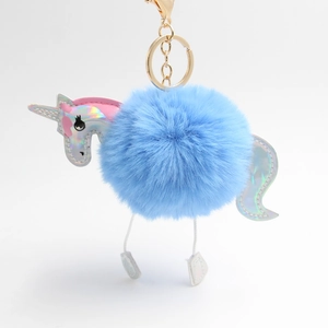 Close-up of blue plush unicorn keychain with iridescent silver details and gold hardware