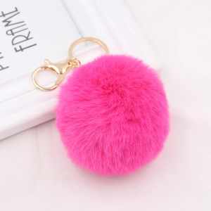 Detail of soft rose red faux fur pompom keychain with golden metal lobster clasp
