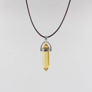 Detail of a yellow hexagonal crystal pendant with a silver metal clasp on a brown cord necklace
