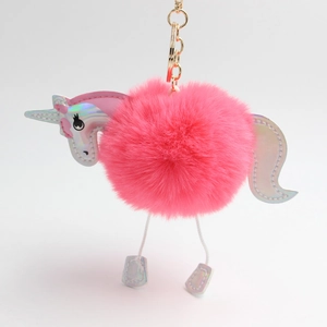 Detail of fluffy pink unicorn pom pom keychain with iridescent metallic parts and gold ring
