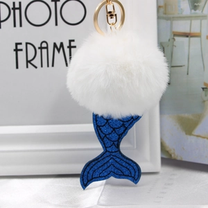 Détail d'un porte-clés pompon blanc avec queue de sirène à paillettes bleues et fermoir doré