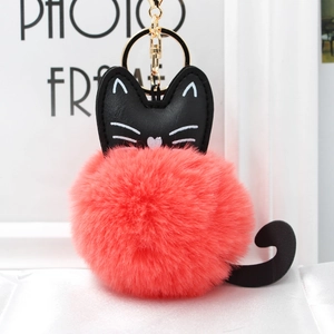 Detail showing coral pink fur pom-pom with black leather cat design and golden keychain