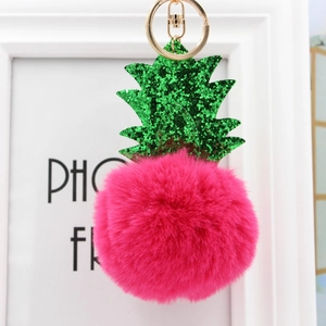 Gros plan sur le porte-clés ananas en fourrure fuchsia avec fermoir en métal doré