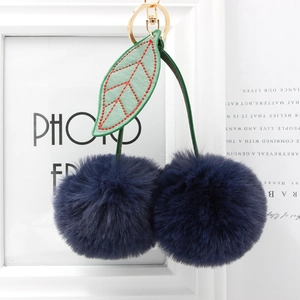 Detailed close-up of navy blue faux fur cherry keychain with green leaves and gold hardware