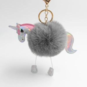 Detail of gray fluffy unicorn keychain with iridescent laser leather and gold metal clasp