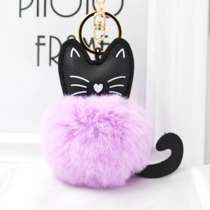 Close-up of cute purple plush kitten pompom keychain with golden metal hardware and black ears