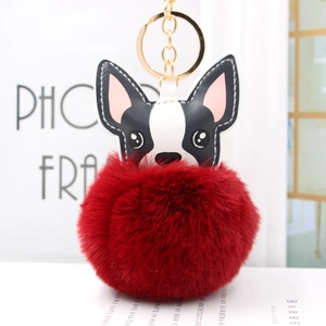 Dettaglio del portachiavi con pompon rosso scuro e ciondolo a forma di cane bianco e nero