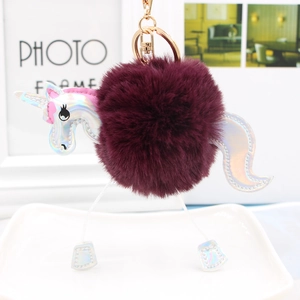 Close-up of fluffy unicorn keychain with burgundy pompom and laser silver details