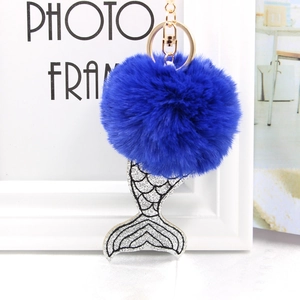 Détail d'un pompon bleu roi en fausse fourrure avec queue de sirène à paillettes argentées