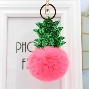Détail d'un porte-clés ananas en fourrure rose avec sequins verts et anneau doré