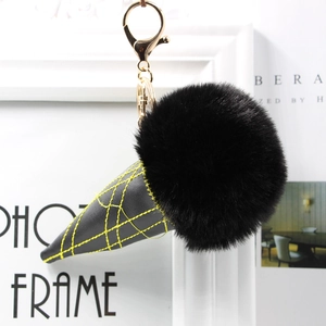 Close-up of black faux fur ice cream cone keychain with gold metal clasp and yellow stitching