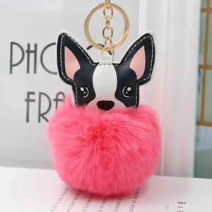 Dettaglio di un portachiavi a forma di cane con pompon rosa e anello in metallo dorato