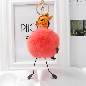 Close-up of a plush pink giraffe bag charm with a golden ring and faux fur ball