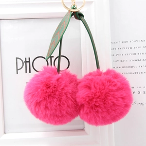 Detail of plush cherry faux fur keychain with pink pom poms and gold ring buckle