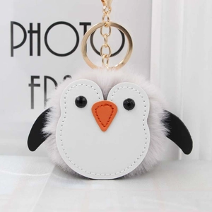 Détail d'un porte-clés pingouin en peluche douce avec pompon gris et fermoir doré chic