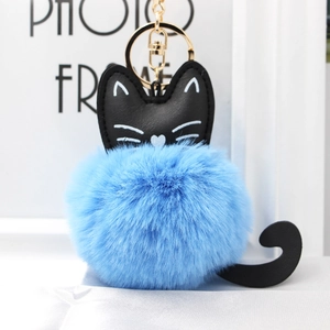 Detail of blue plush cat pom-pom keychain with black faux leather ears and golden metal clip