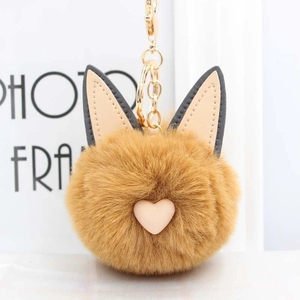 Gros plan d'un porte-clés chat en peluche marron avec cœur rose et chaîne dorée