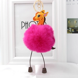 Detail of rose red faux fur pompom keychain with a cute yellow giraffe plush toy charm