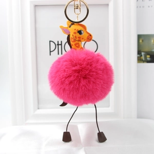 Macro shot of fluffy pink faux fur ball giraffe keychain with golden metal ring and hook