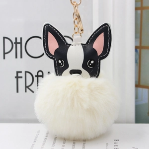 Dettaglio del ciondolo a forma di cane con pompon bianco crema e portachiavi d'oro