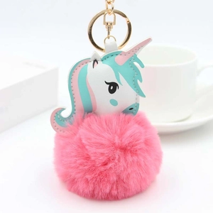 Détail d'un porte-clés pompon en fausse fourrure rose avec breloque licorne en cuir