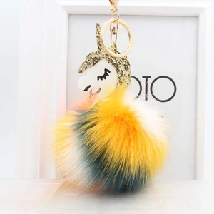 Close-up of fluffy unicorn pompom keychain with golden clip and white glitter leather head