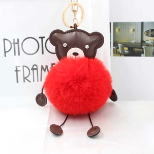 Detailed close-up of a red plush pom pom bear keychain with luxury gold metal hardware