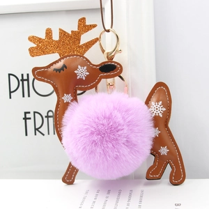 Macro detail of reindeer bag charm featuring purple faux fur pompom and golden glitter antlers