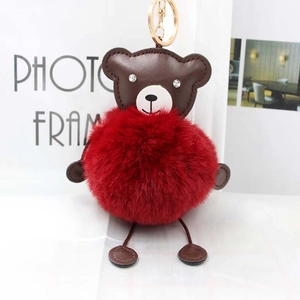 Close-up of a brown PU leather bear keychain with a fluffy red faux fur pompom and gold ring