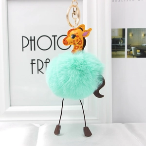 Detail of giraffe plush keychain with mint green faux fur pompom and golden lobster clasp