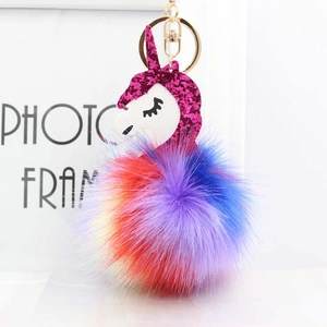 Macro detail of rainbow unicorn keychain with colorful plush pom pom and golden ring