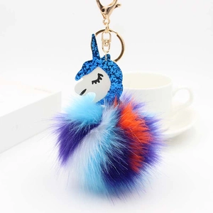Close-up of colorful unicorn pompom keychain with golden metal lobster clasp and blue sequins