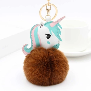 Détail de breloque licorne avec anneau doré et pompon en fausse fourrure marron douce