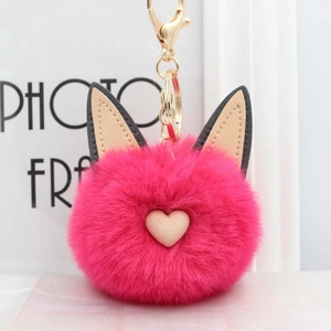 Détail d'un porte-clés pompon chat rose moelleux avec oreilles et fermoir mousqueton doré