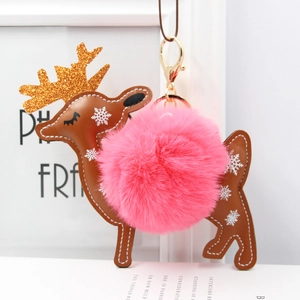 Detail of deer keychain with pink faux fur pompom and golden antlers on bag charm