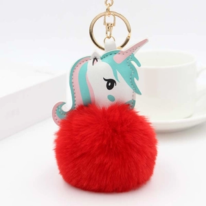 Détail d'un pompon rouge en fausse fourrure et d'un charm licorne coloré avec anneau doré