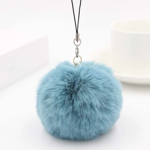 Macro shot of gray-blue faux rabbit fur pom pom charm with silver ring and lanyard