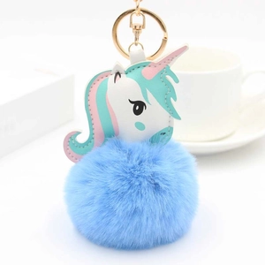 Détail du porte-clés pompon bleu avec pendentif licorne en cuir et mousqueton doré brillant