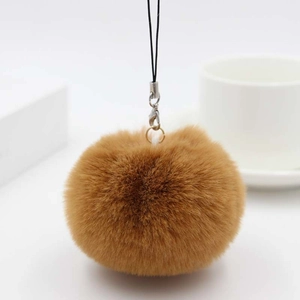 Detailed close-up of a soft brown faux fur pompom keychain with a black lanyard cord