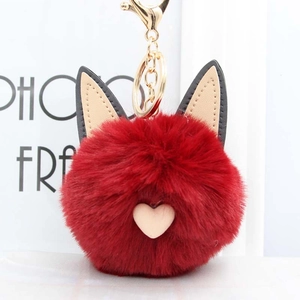 Détail d'un porte-clés en peluche rouge avec oreilles de chat et charme de cœur rose