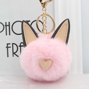 Gros plan d'un porte-clés pompon rose avec oreilles de chat en cuir et fermoir doré