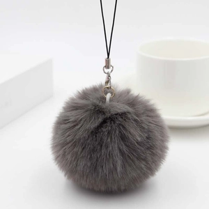 Close-up of fluffy dark grey faux rabbit fur pompom with black strap and metal lobster clasp