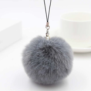 Detail of soft grey faux rabbit fur pom pom with silver lobster clasp and black lanyard