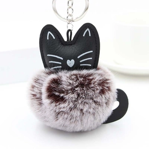 Detail of cute cat keychain with black leather head and soft bicolor plush pompom charm