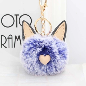 Détail d'un porte-clés pompon chat bleu-violet avec oreilles en cuir et cœur rose