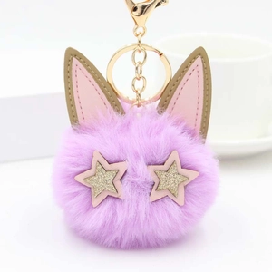 Détail macro du porte-clés pompon chat violet avec des étoiles dorées et oreilles