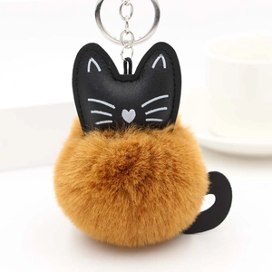 Detail of a handmade cat pompom keychain with brown faux fur and a black leather cat head